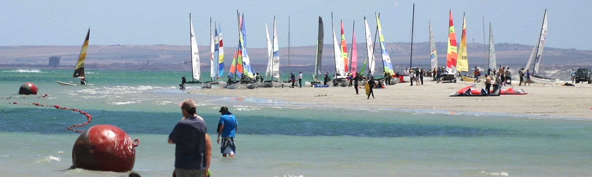 Catamarans pulled up on the beach at Langebaan with the lagoon behind